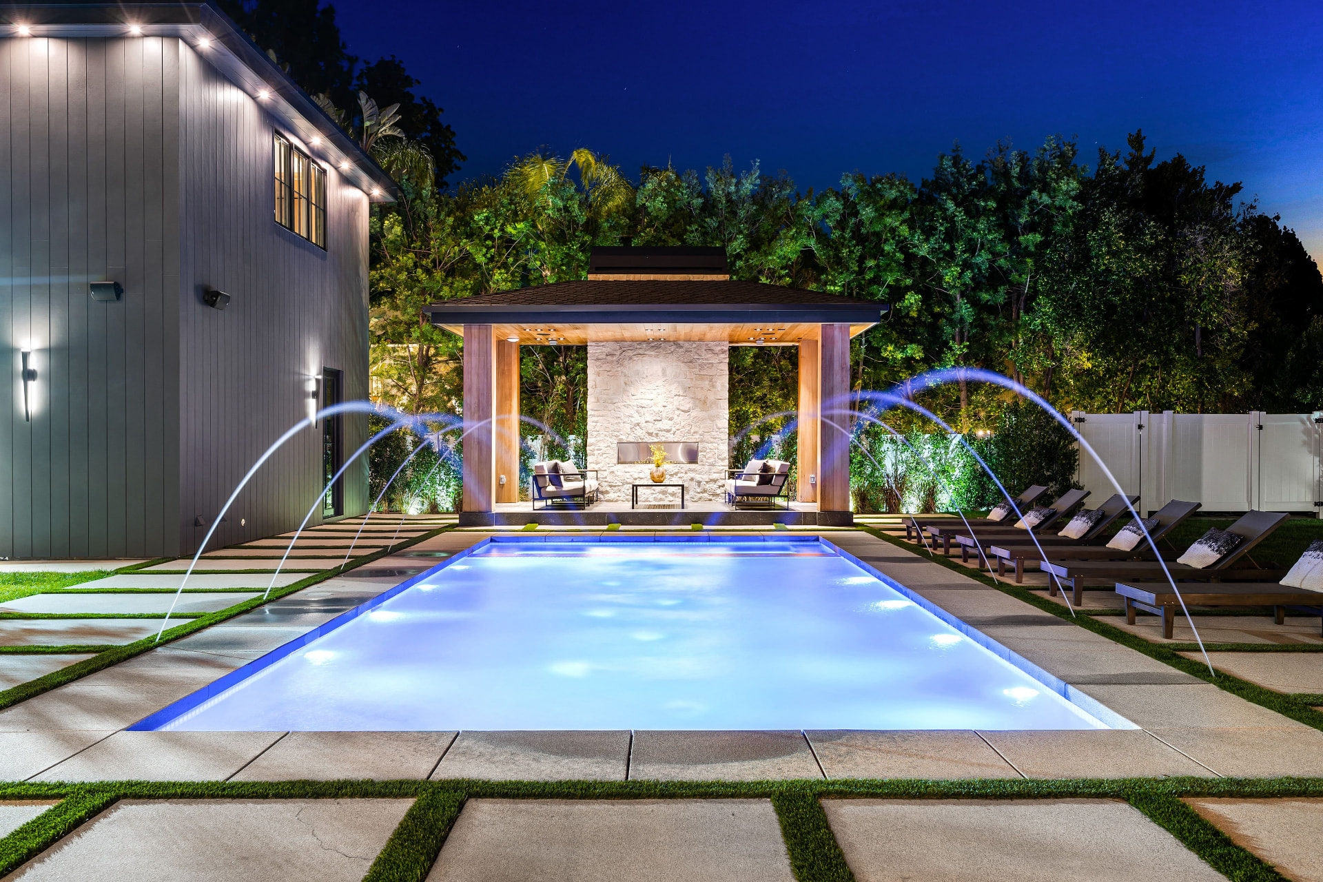 Modern renovated pool with deck jets and lighting at dusk